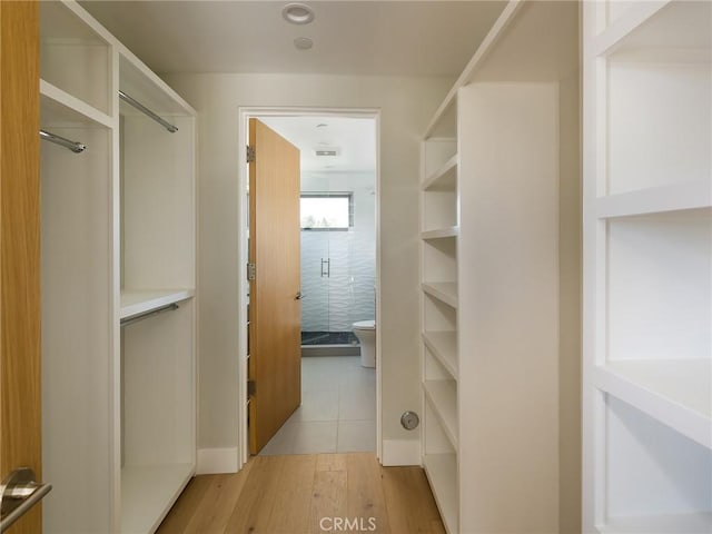 walk in closet with light hardwood / wood-style flooring