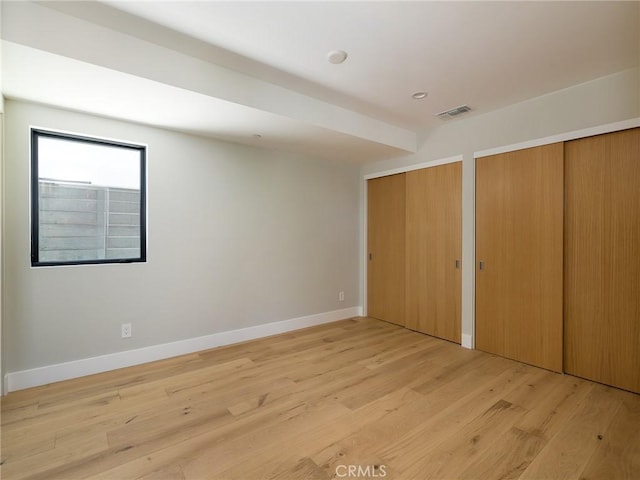 unfurnished bedroom featuring light hardwood / wood-style floors and two closets