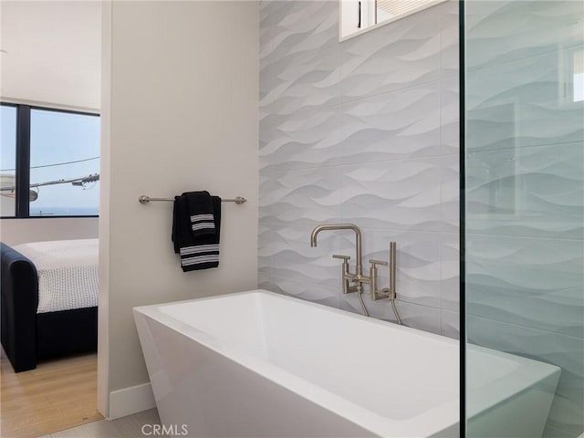 bathroom featuring a healthy amount of sunlight, wood-type flooring, and a tub