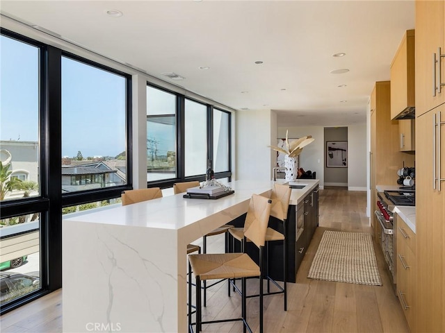 kitchen featuring a center island, range with two ovens, light wood-type flooring, and light brown cabinetry