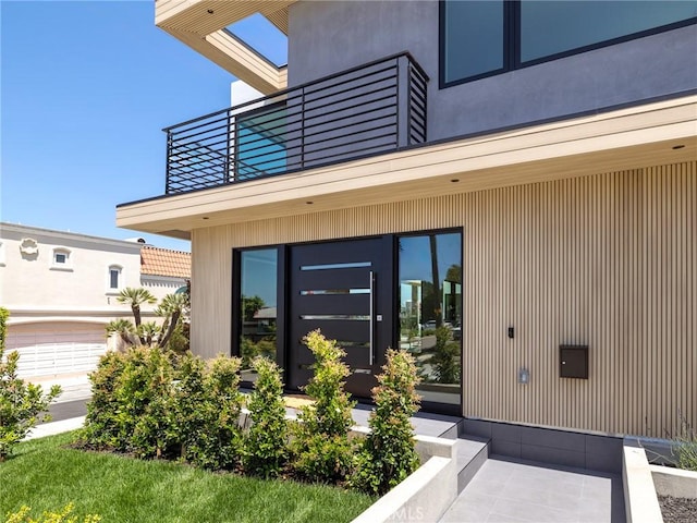 view of exterior entry with a balcony and a garage