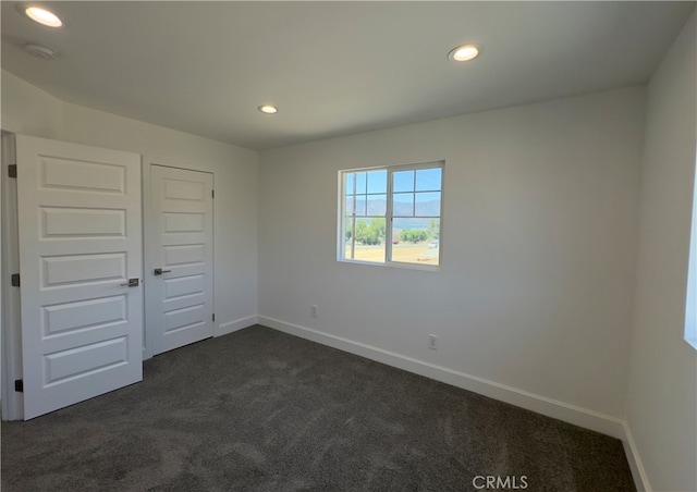 unfurnished bedroom featuring a closet and dark carpet