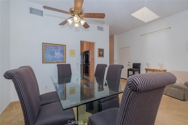 dining room with light carpet, ceiling fan, and a skylight