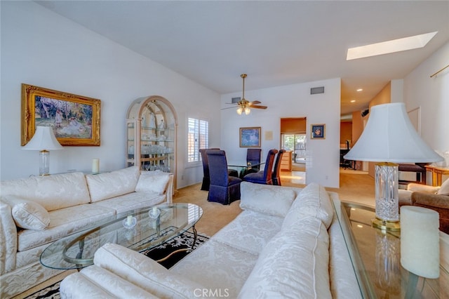 living room featuring ceiling fan, light colored carpet, and a skylight