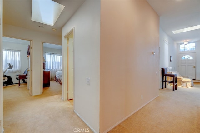 hall with a skylight and light colored carpet