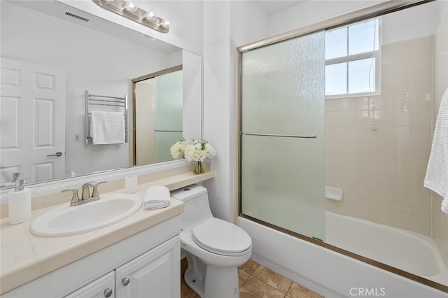 full bathroom featuring shower / bath combination with glass door, tile patterned flooring, vanity, and toilet