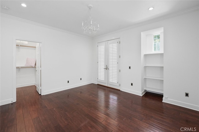 empty room featuring a chandelier, french doors, dark hardwood / wood-style floors, and crown molding