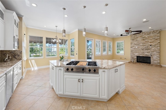 kitchen featuring white cabinetry, hanging light fixtures, a kitchen island, ceiling fan with notable chandelier, and appliances with stainless steel finishes