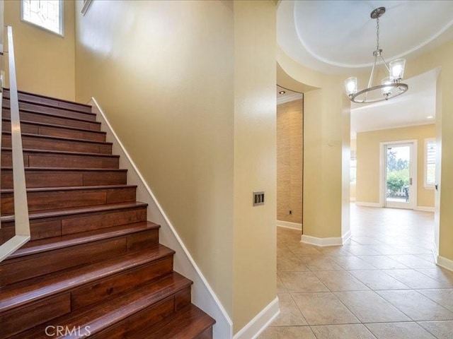 stairs featuring tile patterned floors and a chandelier