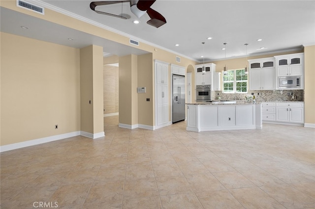 kitchen with light stone countertops, crown molding, built in appliances, white cabinets, and a center island