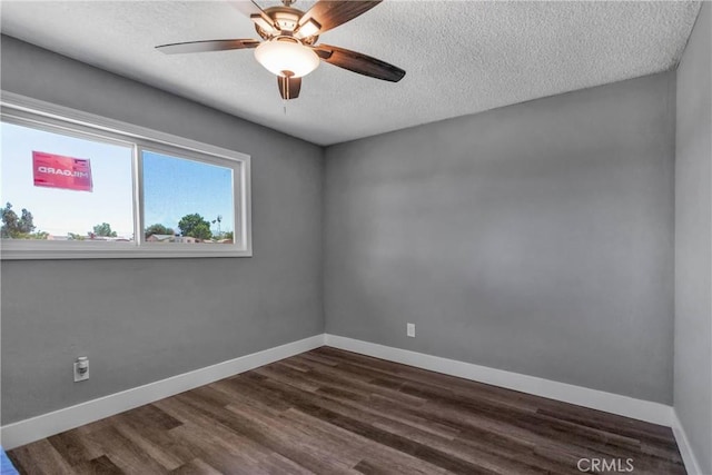 spare room featuring baseboards, dark wood-type flooring, ceiling fan, and a textured ceiling