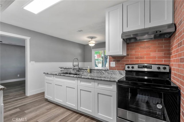 kitchen with electric range, visible vents, a sink, under cabinet range hood, and white cabinets