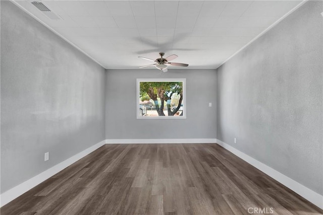 unfurnished room with visible vents, dark wood-type flooring, baseboards, and ornamental molding