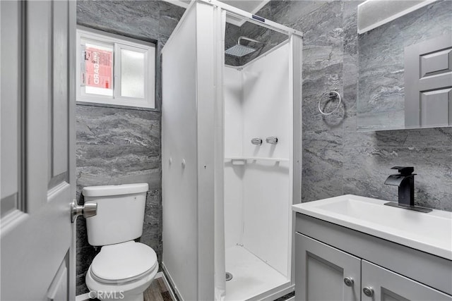 full bathroom featuring vanity, tile walls, toilet, and a shower stall