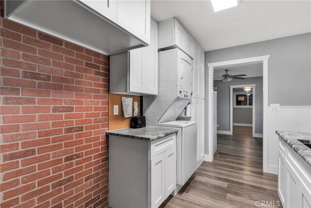 kitchen with wood finished floors, white cabinetry, ceiling fan, and stacked washer and dryer