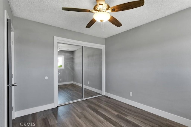 unfurnished bedroom featuring dark wood-type flooring, baseboards, a closet, and a textured ceiling