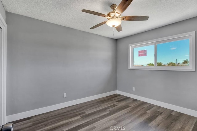 empty room with dark wood-style floors, ceiling fan, a textured ceiling, and baseboards