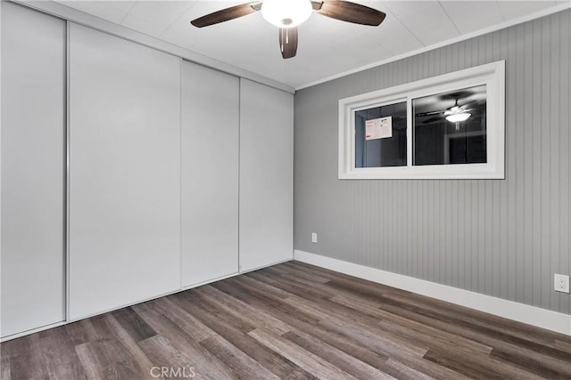 unfurnished bedroom with a closet, baseboards, wood finished floors, and a ceiling fan