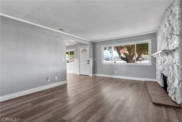 unfurnished living room with visible vents, a textured ceiling, a stone fireplace, and wood finished floors