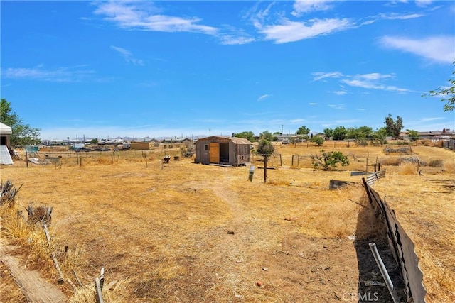 view of yard with an outbuilding, a rural view, and fence