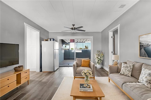 living area featuring ceiling fan, baseboards, and wood finished floors