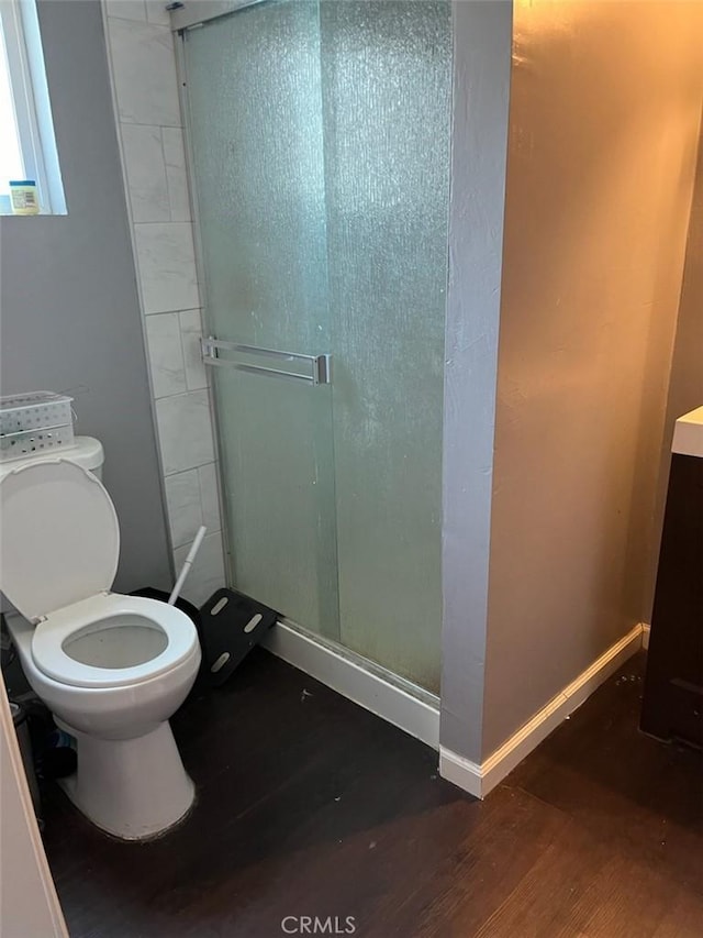 bathroom with hardwood / wood-style floors, toilet, and a shower with shower door