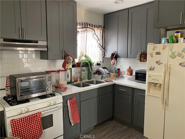 kitchen featuring white appliances, dark wood-type flooring, gray cabinetry, and sink