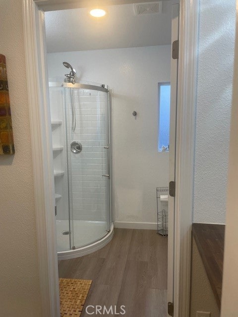 bathroom featuring a shower with shower door and wood-type flooring