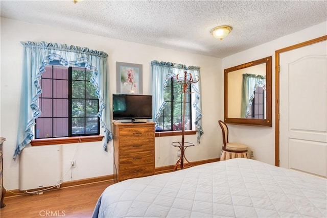 bedroom featuring hardwood / wood-style flooring, radiator heating unit, and a textured ceiling