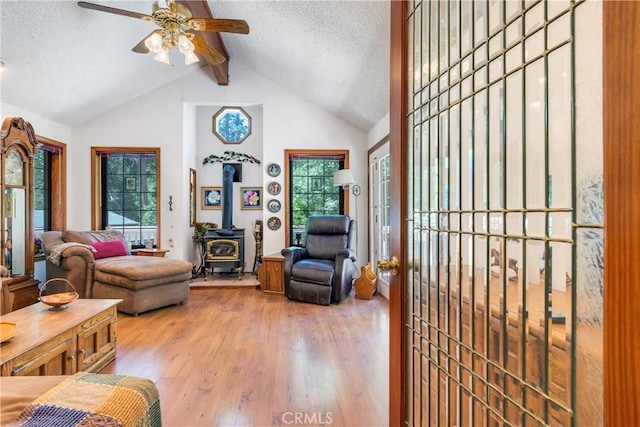 living room featuring hardwood / wood-style flooring, a wood stove, a wealth of natural light, and beam ceiling