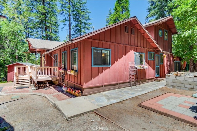 view of property exterior featuring a wooden deck and a patio