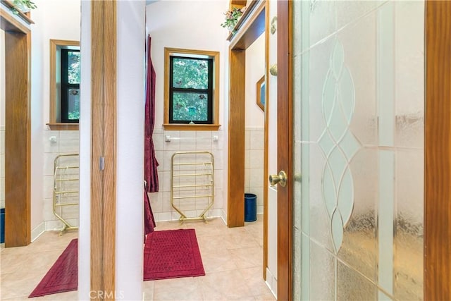 corridor featuring french doors, tile walls, and light tile patterned floors