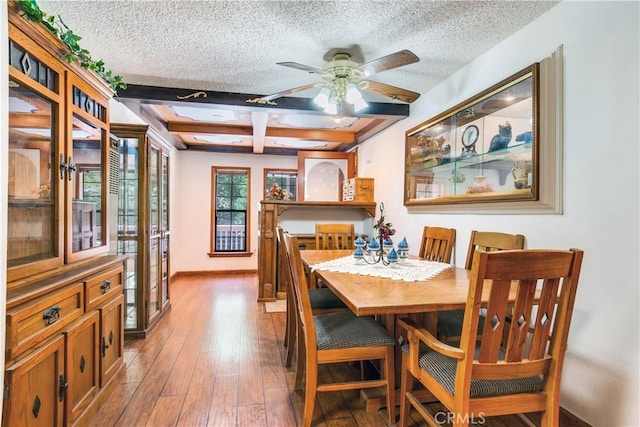 dining space featuring coffered ceiling, ceiling fan, light hardwood / wood-style floors, a textured ceiling, and beam ceiling