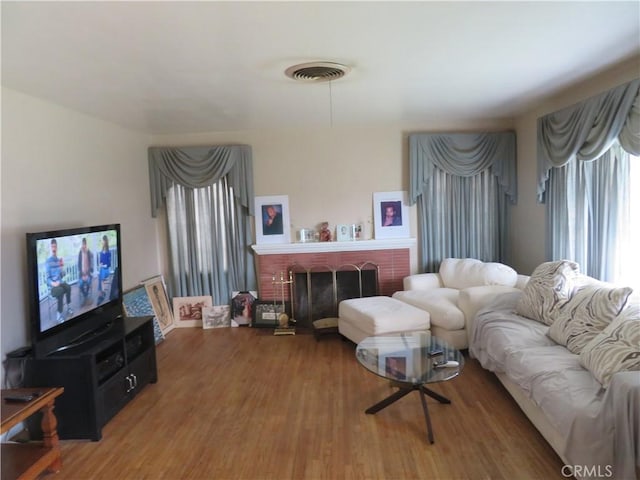 living room with wood-type flooring and a brick fireplace