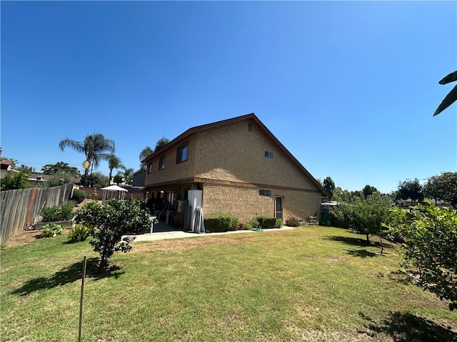 back of house featuring a lawn and a patio