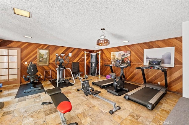 workout area with wooden walls and a textured ceiling