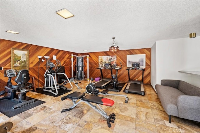 workout room featuring a textured ceiling and wooden walls