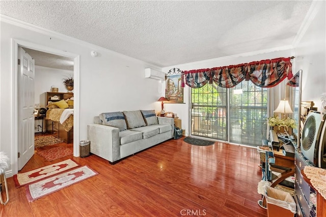 living room featuring wood-type flooring, a textured ceiling, a wall unit AC, and ornamental molding