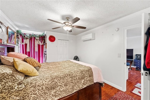 bedroom with a wall mounted AC, ceiling fan, crown molding, wood-type flooring, and a closet