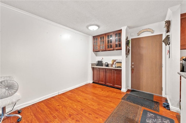 bar featuring light hardwood / wood-style floors, crown molding, and a textured ceiling