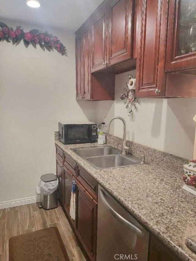 kitchen featuring dishwasher, sink, light hardwood / wood-style floors, and light stone counters