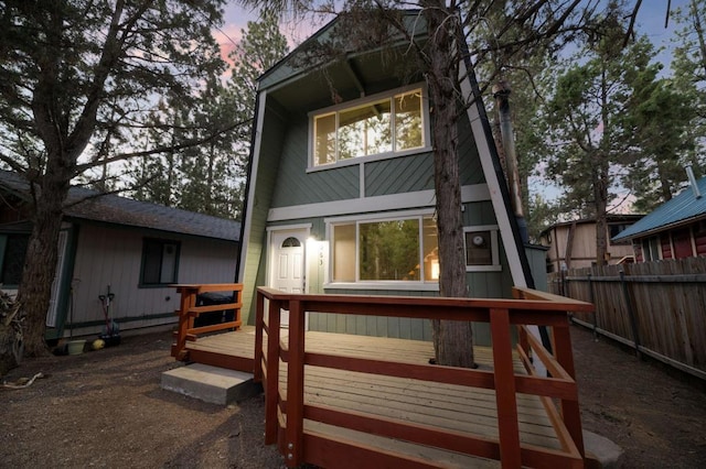 back house at dusk featuring a wooden deck