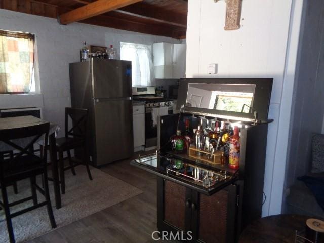 kitchen featuring range with electric stovetop, stainless steel refrigerator, beamed ceiling, and wood-type flooring