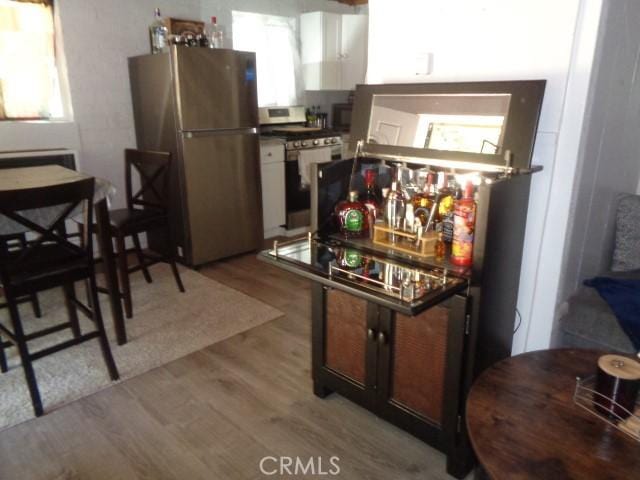 kitchen featuring a wealth of natural light, light wood-type flooring, white stove, and stainless steel refrigerator