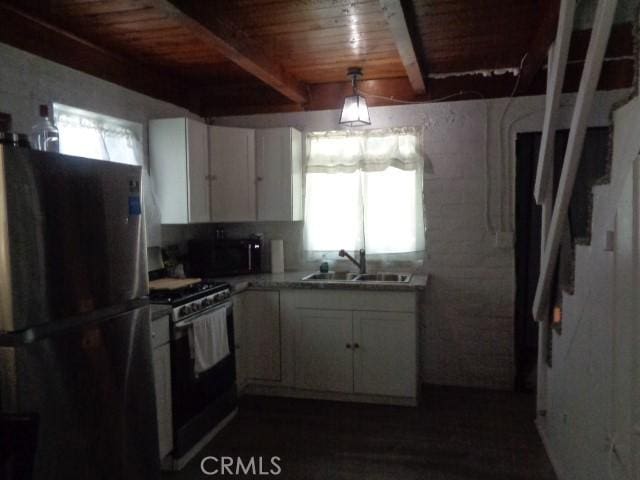 kitchen with white gas range, white cabinetry, sink, wooden ceiling, and refrigerator