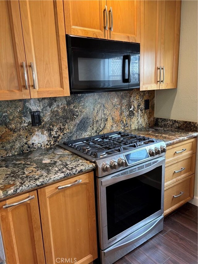 kitchen with dark stone countertops, backsplash, dark hardwood / wood-style floors, and stainless steel gas stove