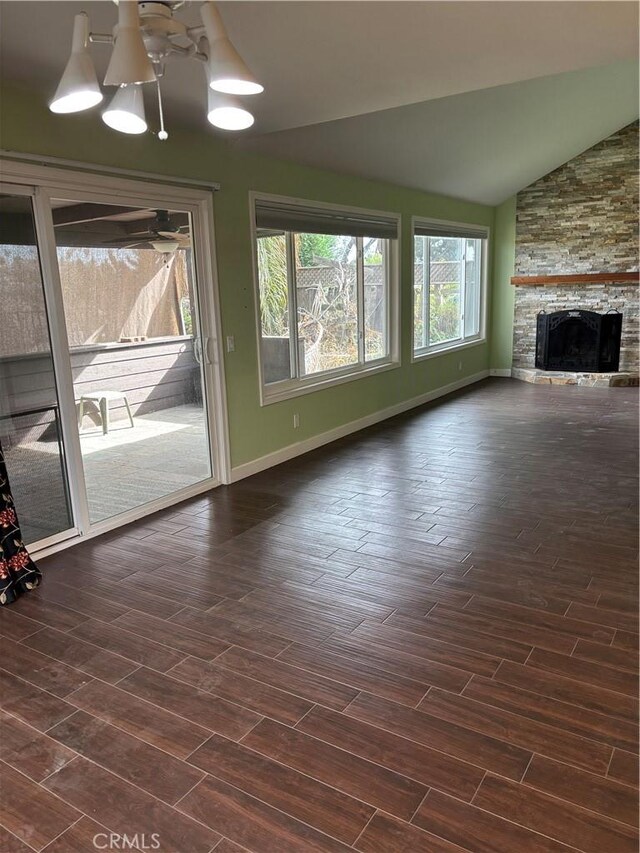 unfurnished living room featuring a notable chandelier, a stone fireplace, dark hardwood / wood-style flooring, and lofted ceiling