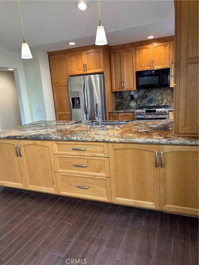 kitchen featuring dark stone countertops, appliances with stainless steel finishes, dark wood-type flooring, and decorative light fixtures