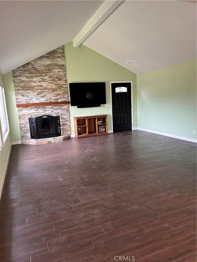 unfurnished living room with a stone fireplace and vaulted ceiling with beams