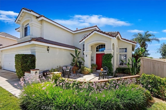 mediterranean / spanish home featuring a garage and a patio area